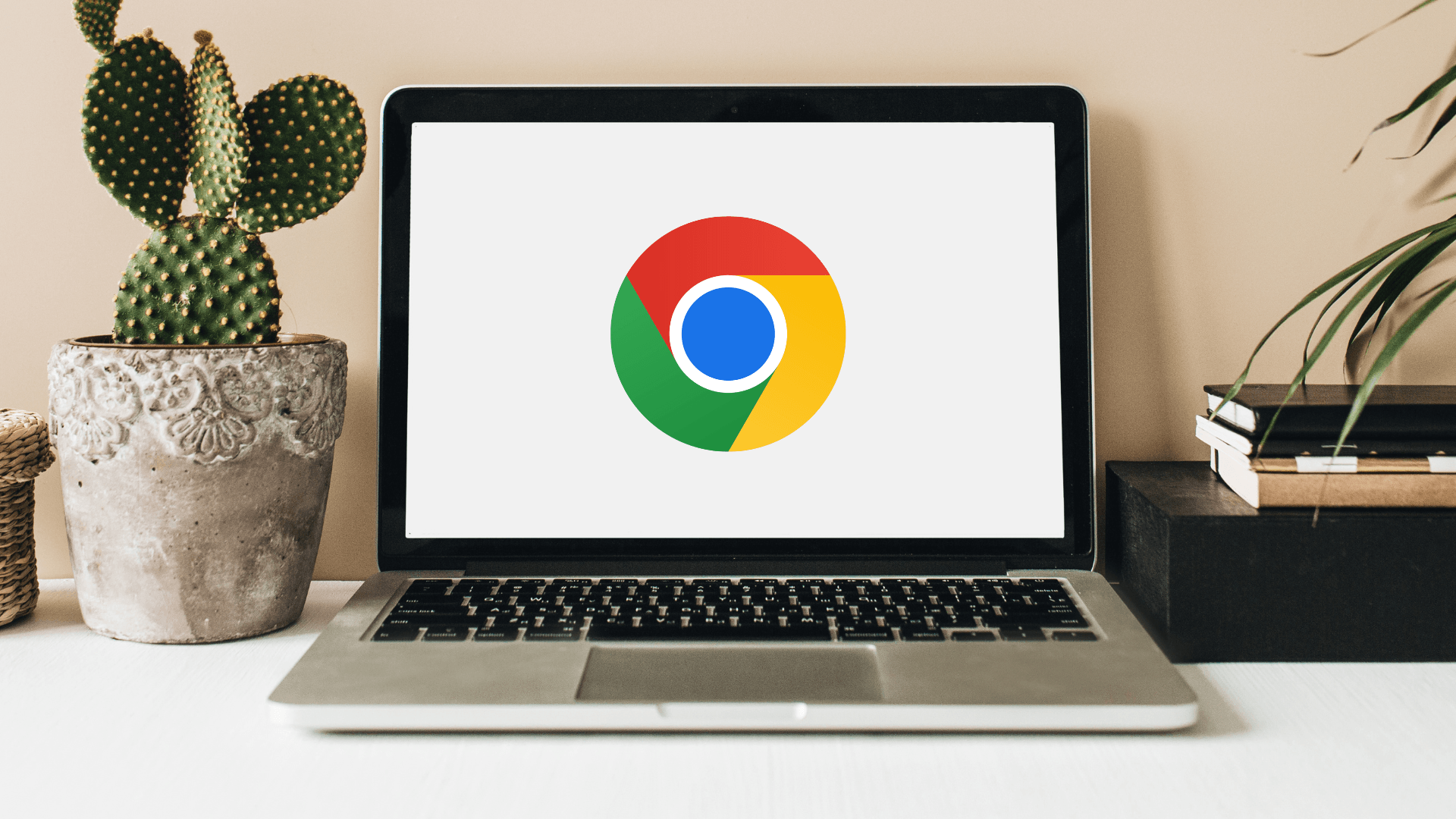Laptop on a desk with Google Chrome logo on screen, beside a potted cactus and books, relating to the best browser for Windows 11.