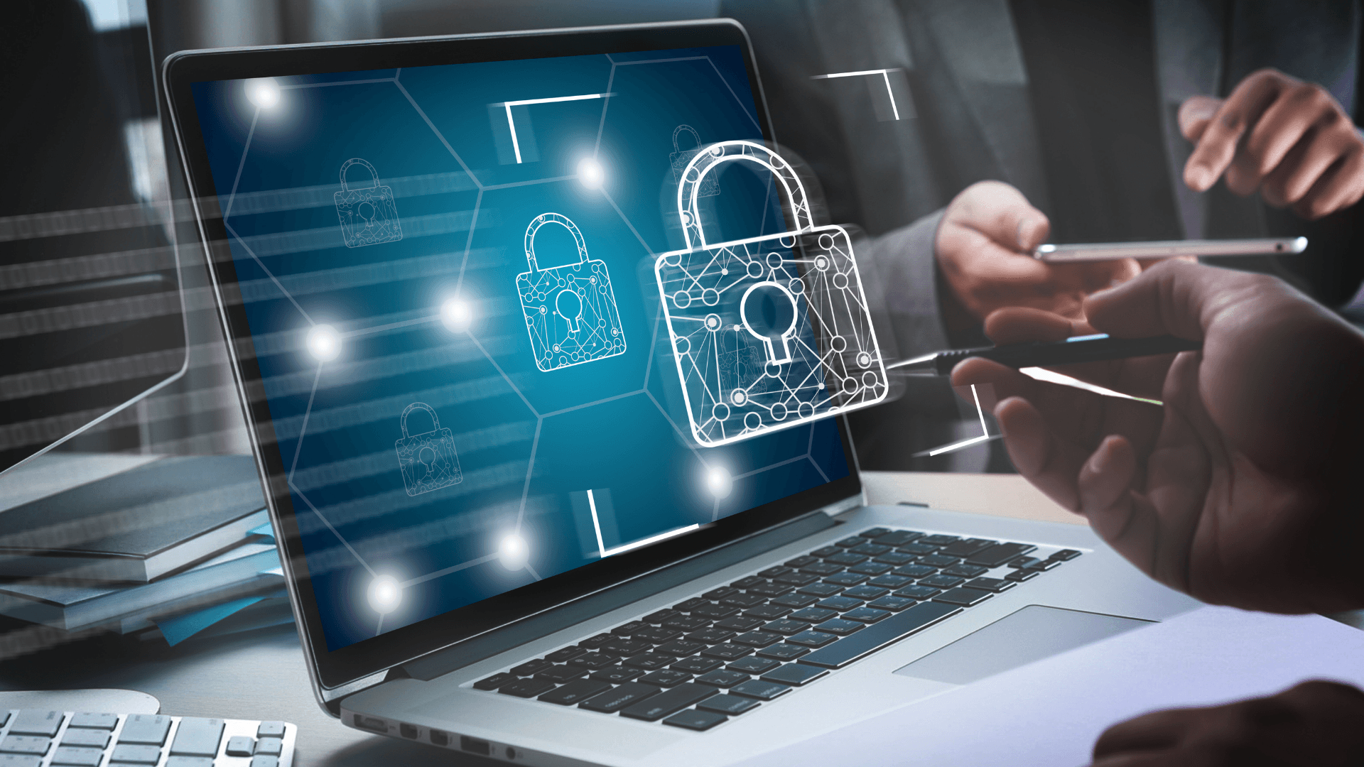 A laptop displays digital padlock graphics, symbolizing cybersecurity, with two people analyzing data.