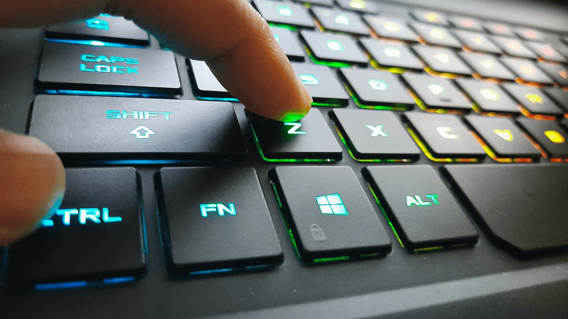 Fingers hovering over the Ctrl and Z keys on a blue RGB keyboard, representing the shortcut for undo and the shortcut for redo